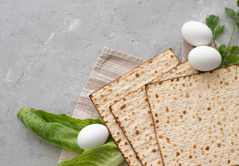 Layout of  Traditional Matzah prepared for Passover with egg, green salad and parsley on gray background. top view. Spring Holiday of Jewish people. Fasting time