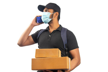 Portrait Of Young Delivery Man wearing face mask Holding parcel and talking on the mobile phone