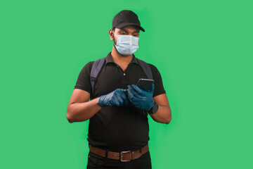 Portrait Of Young Delivery Man wearing face mask and hand Glove with mobile phone