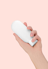 Skin care concept. Woman's hand holding white cosmetic tube isolated on pink background, mockup. Cosmetic branding mockup.