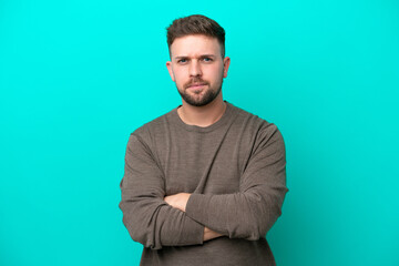Young caucasian man isolated on blue background with unhappy expression