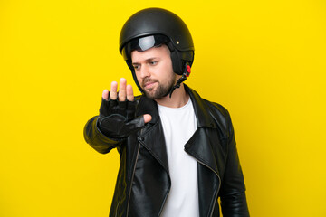 Young caucasian man with a motorcycle helmet isolated on yellow background making stop gesture and disappointed
