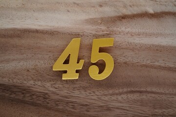 Golden Arabic numerals on a real brown and white wooden floor number 45
