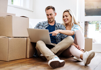 Browsing online for interior design ideas. Shot of a young couple using a laptop while moving house.