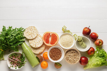 Healthy products with measuring tape on white wooden background