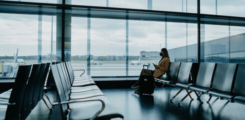 Young woman sitting at the empty airport hall. Waiting for flight. Cover photo