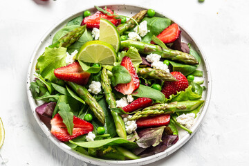 Healthy salad. green asparagus, strawberry, rocket and cottage cheese. Healthy balanced eating. Delicious balanced food concept, top view