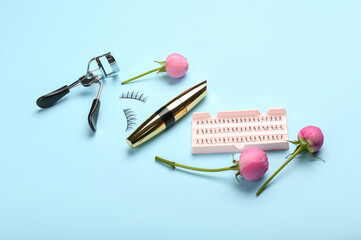 Composition with mascara, eyelash curler, false eyelashes and rose flowers on color background