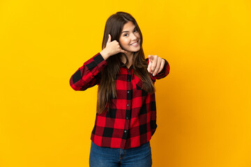 Teenager Brazilian girl isolated on yellow background making phone gesture and pointing front