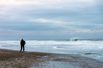 Ein Mann geht im Morgengrauen am Nordseestrand spazieren