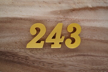 Golden Arabic numerals on a real brown and white wooden floor number 243