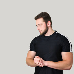 Fototapeta premium Young athletic man standing with arms crossed and looking down over isolated background