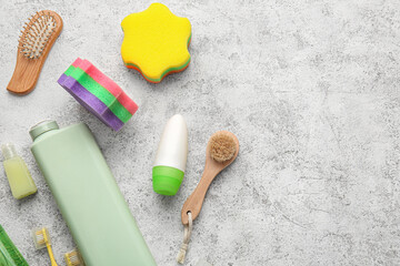 Bottles of cosmetic products and bath accessories on light background