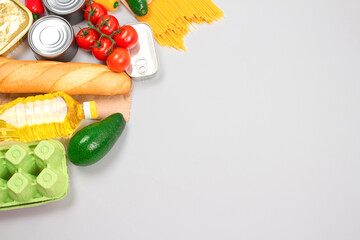 Different groceries, food donations on gray background with copy space - pasta, vegatables, canned...