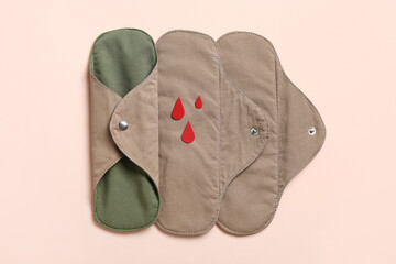Reusable menstrual pads and paper blood drops on pink background