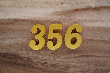 Golden Arabic numerals on a real brown and white wooden floor number 356