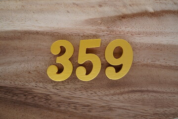 Golden Arabic numerals on a real brown and white wooden floor number 359
