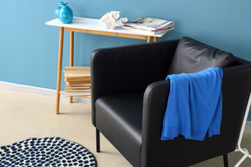 Modern armchair and table with decor near color wall