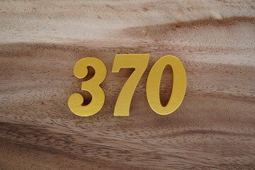 Golden Arabic numerals on a real brown and white wooden floor number 370
