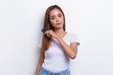 young beautiful asian woman combing long hair with a comb isolated on white background
