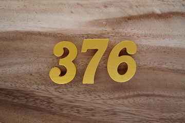 Golden Arabic numerals on a real brown and white wooden floor number 376