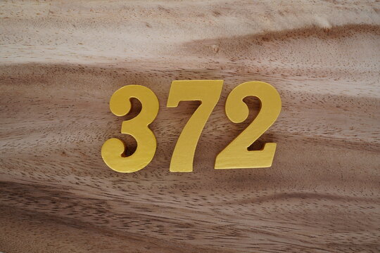 Golden Arabic numerals on a real brown and white wooden floor number 372