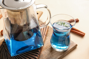 Teapot and cup of blue tea on color background, closeup
