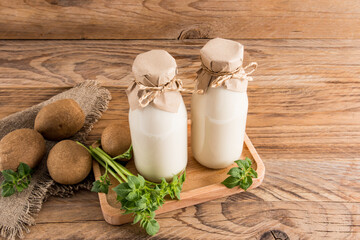 vegan vegetable potato milk in two bottles on a wooden tray and a rustic table. drink substitute. healthy eating.