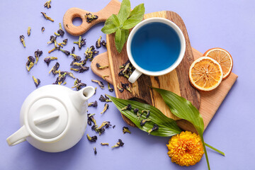 Composition with cup of blue tea and dried butterfly pea flowers on color background