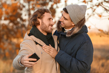 Fototapeta premium Happy gay couple taking selfie in autumn park