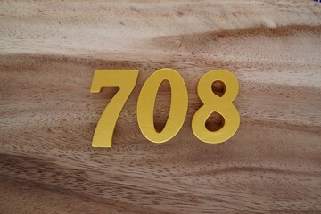 Golden Arabic numerals on a real brown and white wooden floor number 708