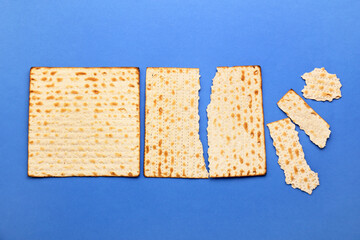 Torn Jewish flatbread matza for Passover on blue background