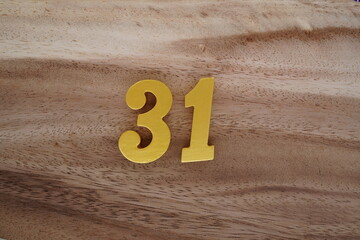 Golden Arabic numerals on a real brown and white wooden floor number 31.
