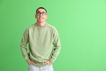 Handsome young Asian man in knitted sweater on green background