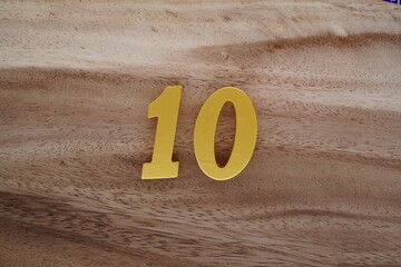 Golden Arabic numerals on real wooden floor with brown pattern.