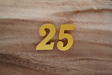 Golden Arabic numerals on a real brown and white wooden floor number 25
