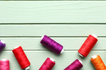 Sewing threads on color wooden background