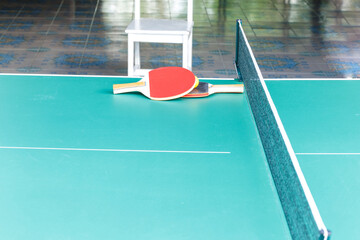Ping pong ball with paddle on green table tennis.