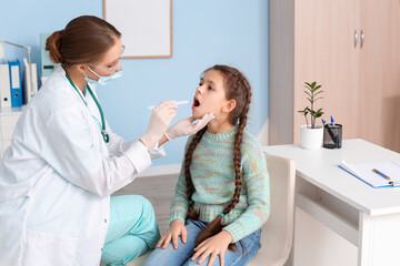 Doctor examining little girl with sore throat in clinic