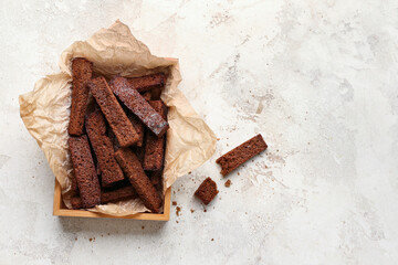 Wooden box with rye croutons on light background