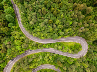 Winding road from high mountain pass, in summer time. Aerial view by drone . Romania
