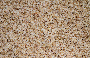 Rolled oats or oat flakes, whole-grain cereal background texture.