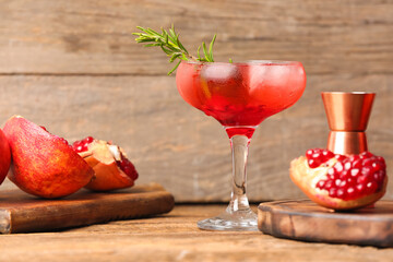 Glass of tasty pomegranate cocktail on wooden background