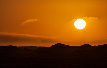 Sun and orange sky, wind eroded rock formations, Egyptian White Desert. Western Desert, Egypt