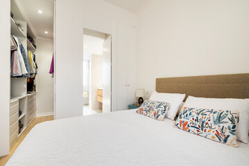 King size bed with flowery cushions in bedroom with dressing room and en-suite bathroom