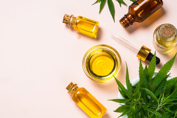 Cannabis oil in glass bowl and cosmetic bottles with dropper and fresh leaves at pastel background. Flat lay image with copy space.