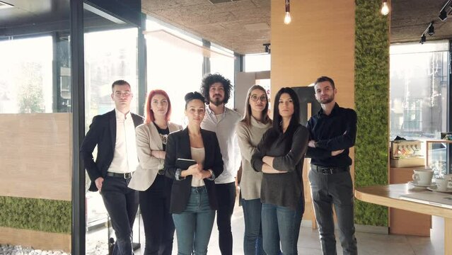 Portrait of young successful confident people, colleagues holding laptops and posing in a modern office building.
