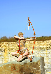 A Stone Age young woman is dressed as Neanderthal warrior. 
Her body and face is covered with mud...