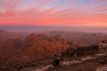 Woman tourist waiting for sunrise on the summit of the Holy Mount Moses (Mount Horeb, Mount Sinai or Jabal Mousa), Egypt, North Africa. Low exposure	