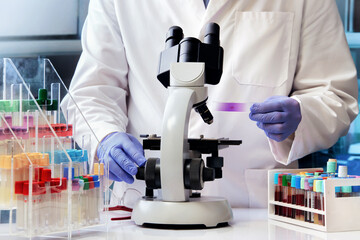 scientific microbiologist preparing blood samples for analysis under the microscope. research...